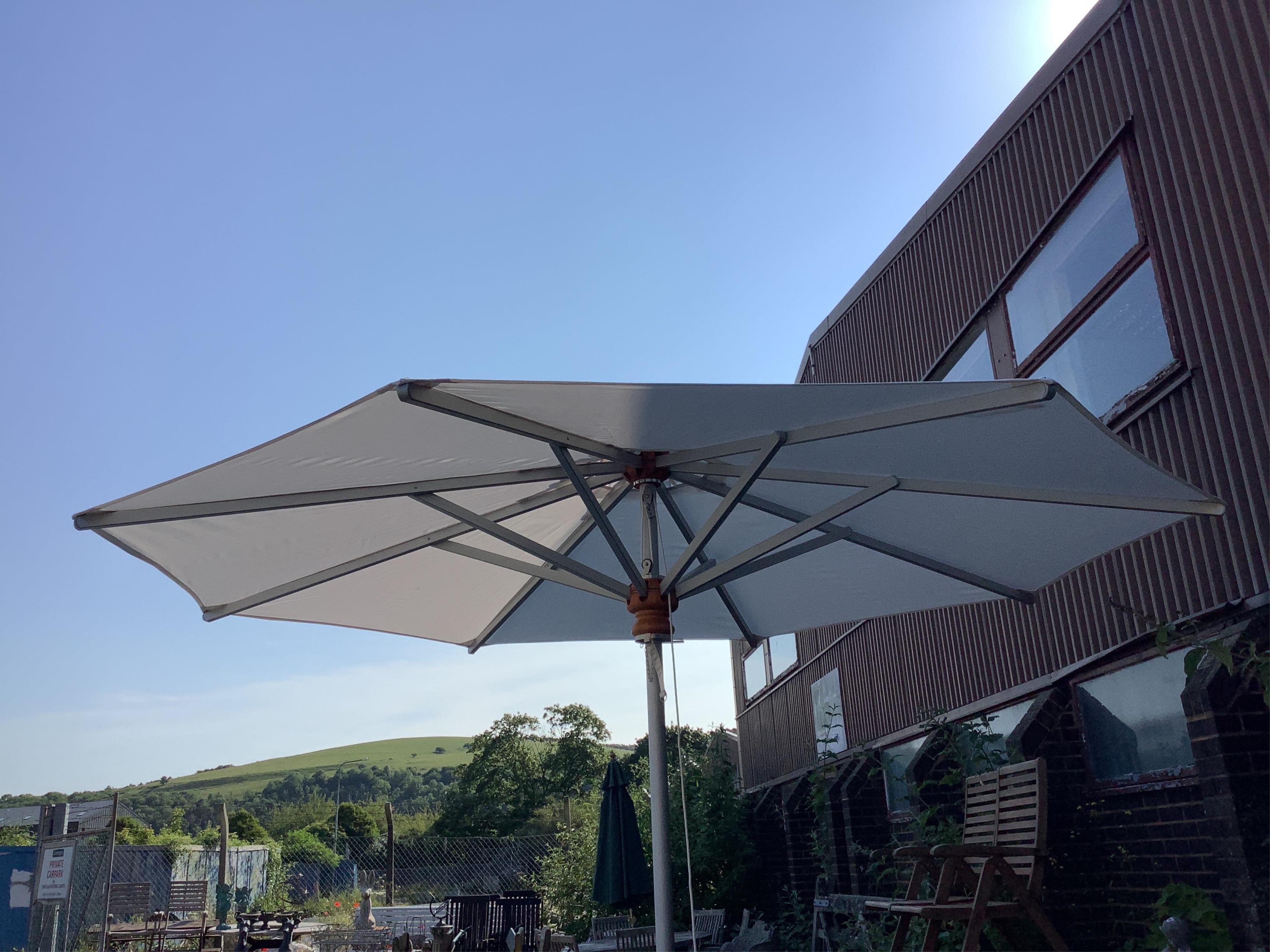 A Barlow Tyrie 10ft diameter white canvas garden parasol with cast iron base and canvas cover. Condition - parasol good, metal base fair